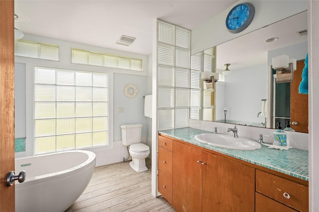 815 5th St, San Leon, TX 77539 - bathroom with a freestanding tub, wood finished floors, vanity, toilet, and tile walls