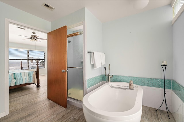 815 5th St, San Leon, TX 77539 - ensuite bathroom featuring a freestanding bath, a shower stall, tile walls, wood finished floors, and a wainscoted wall