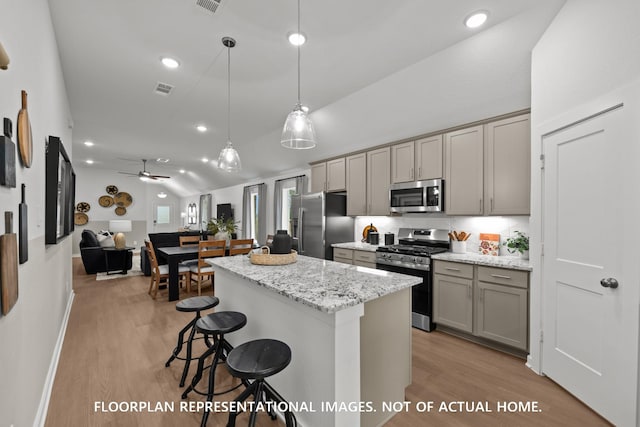 8043 Kay Harbor Dr, Cypress, TX 77433 - kitchen featuring stainless steel appliances, gray cabinets, vaulted ceiling, light wood-style flooring, and a kitchen breakfast bar