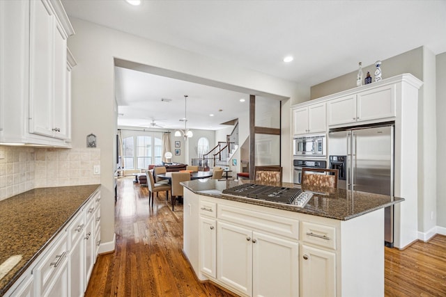 574 Bomar St, Houston, TX 77006 - kitchen featuring stainless steel appliances, dark wood-style flooring, ceiling fan, dark stone counters, and decorative backsplash