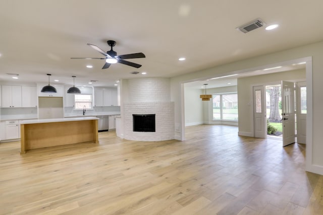 2519 Parana Dr, Houston, TX 77080 - unfurnished living room featuring healthy amount of natural light, recessed lighting, ceiling fan, light wood finished floors, and a brick fireplace