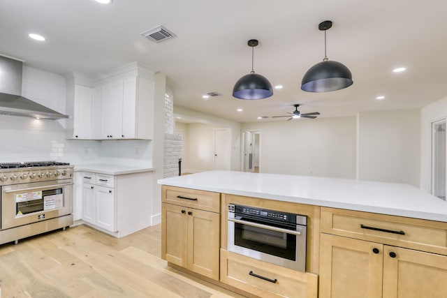 2519 Parana Dr, Houston, TX 77080 - kitchen featuring appliances with stainless steel finishes, wall chimney range hood, light wood-style flooring, a ceiling fan, and light countertops