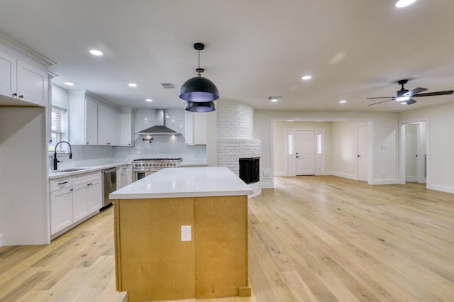 2519 Parana Dr, Houston, TX 77080 - kitchen with wall chimney exhaust hood, stainless steel appliances, a sink, a fireplace, and ceiling fan