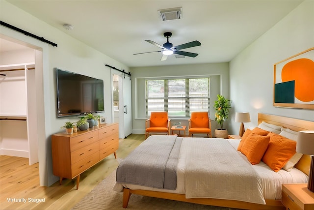 2519 Parana Dr, Houston, TX 77080 - bedroom featuring a barn door, light wood finished floors, baseboards, and a ceiling fan