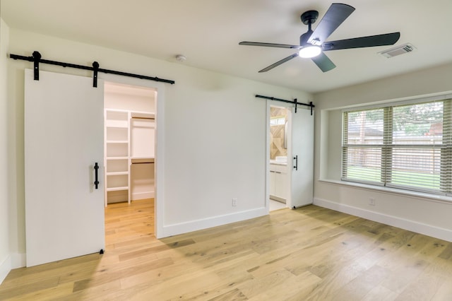 2519 Parana Dr, Houston, TX 77080 - unfurnished room featuring a barn door, ceiling fan, light wood-style flooring, and baseboards