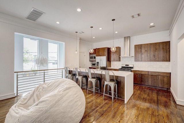 5317 Lillian St, Houston, TX 77007 - kitchen featuring wall chimney range hood, stainless steel appliances, a kitchen bar, light countertops, and tasteful backsplash