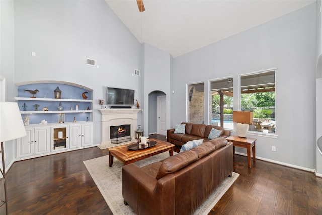 25303 Hall Meadow Ln, Katy, TX 77494 - living area featuring high vaulted ceiling, wood finished floors, arched walkways, a lit fireplace, and baseboards