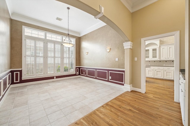 1214 Turnbury Oak Ln, Houston, TX 77055 - spare room with arched walkways, crown molding, light wood-style flooring, wainscoting, and a decorative wall