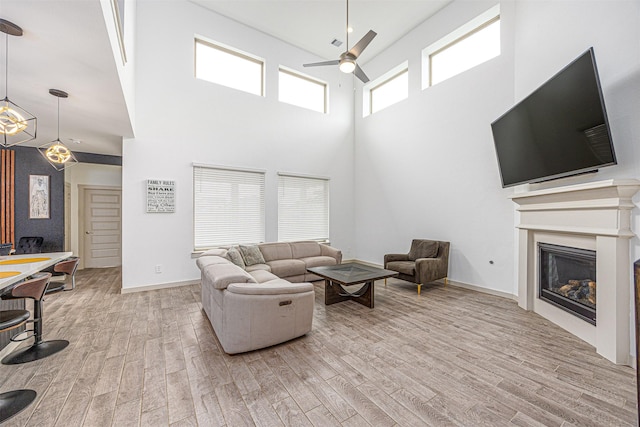 3330 Black Gore Creek Dr, Katy, TX 77494 - living area featuring a ceiling fan, light wood-type flooring, a towering ceiling, a glass covered fireplace, and a chandelier