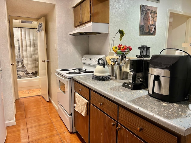 12660 Ashford Point Dr Unit 811, Houston, TX 77082 - kitchen with under cabinet range hood, white electric range, a textured wall, light countertops, and brown cabinetry