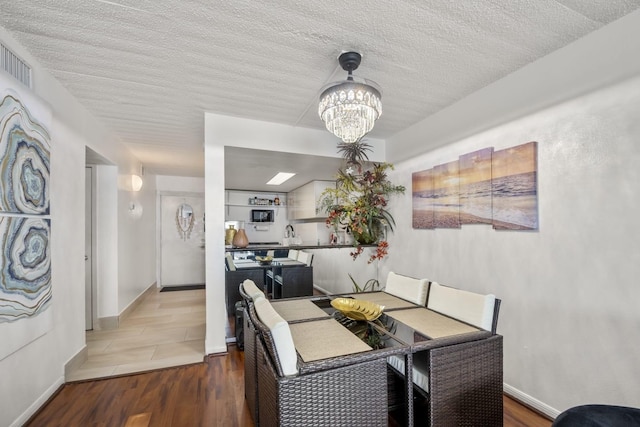 7310 Seawall Blvd Unit 309, Galveston, TX 77551 - dining room featuring a chandelier, wood finished floors, baseboards, and a textured ceiling