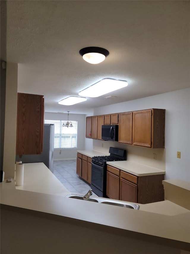 5515 Pimberton Ln, Spring, TX 77379 - kitchen featuring black appliances, light countertops, brown cabinetry, a chandelier, and a sink