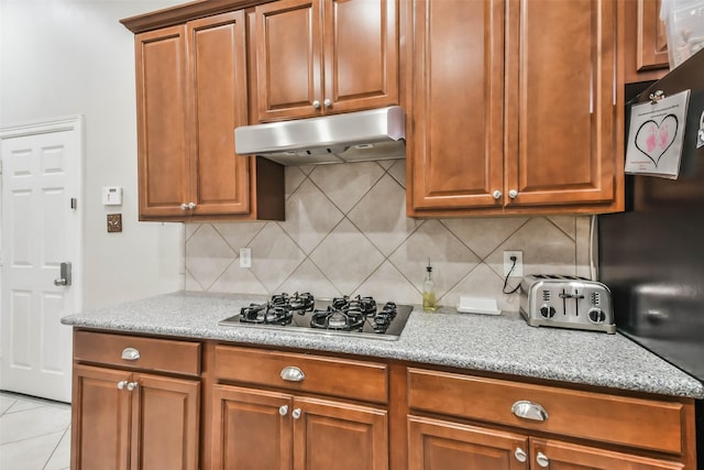 12202 Salt River Valley Ln, Humble, TX 77346 - kitchen featuring under cabinet range hood, stainless steel gas stovetop, decorative backsplash, light stone counters, and brown cabinets