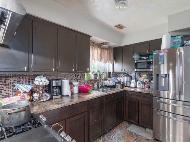 14914 Lawther St, Channelview, TX 77530 - kitchen featuring appliances with stainless steel finishes, a sink, backsplash, light stone finish flooring, and a textured ceiling