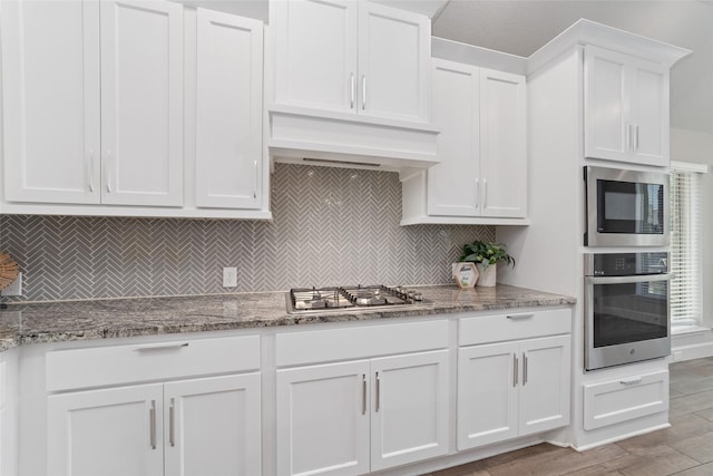 18402 Ingliston Ln, Richmond, TX 77407 - kitchen with stainless steel appliances, white cabinets, tasteful backsplash, and light stone counters