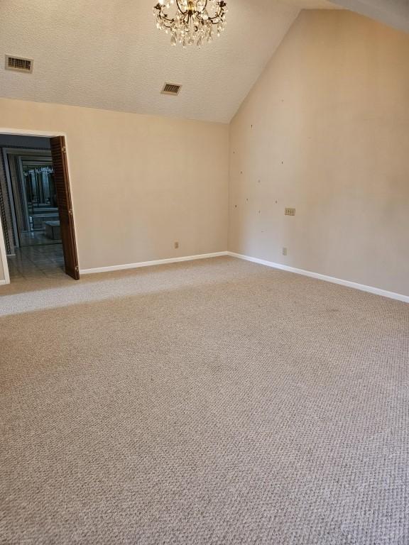 19634 Enchanted Oaks Dr, Spring, TX 77388 - carpeted spare room featuring vaulted ceiling, a chandelier, baseboards, and a textured ceiling