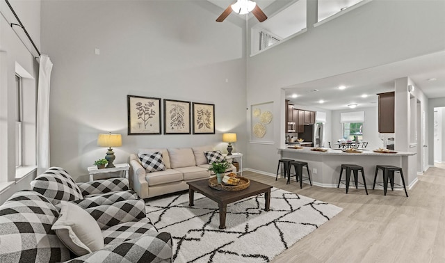 18817 Lucas Michael Way, New Caney, TX 77357 - living room featuring light wood-style floors, a high ceiling, baseboards, and a ceiling fan