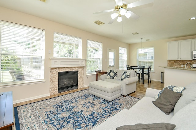 4134 Foxbrush Ln, Sugar Land, TX 77479 - living room featuring light wood-style flooring, plenty of natural light, ceiling fan, and a fireplace with flush hearth
