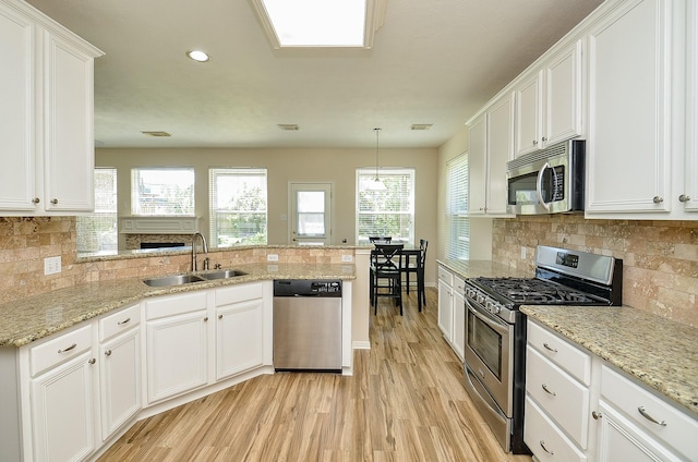 4134 Foxbrush Ln, Sugar Land, TX 77479 - kitchen with stainless steel appliances, a sink, light wood-style flooring, a peninsula, and white cabinetry