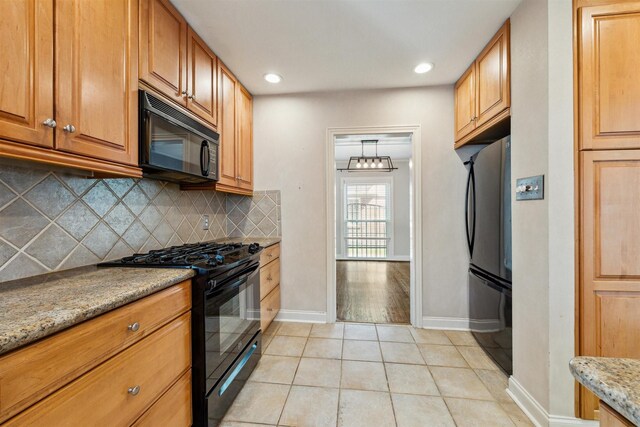 6649 Fairfield St, Houston, TX 77023 - kitchen featuring black appliances, light tile patterned floors, decorative backsplash, baseboards, and light stone countertops