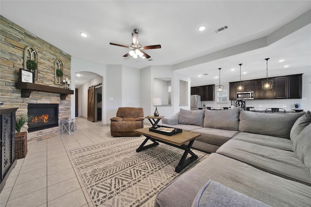 28111 Middlewater View Ln, Katy, TX 77494 - living room featuring light tile patterned flooring, ceiling fan, arched walkways, recessed lighting, and a stone fireplace
