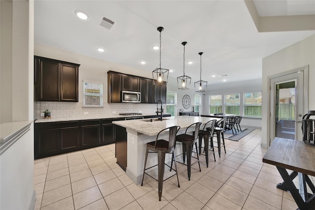 28111 Middlewater View Ln, Katy, TX 77494 - kitchen featuring appliances with stainless steel finishes, light tile patterned floors, backsplash, a center island with sink, and recessed lighting