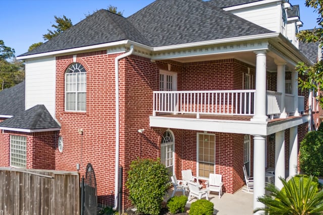18226 Ennsbury Dr, Houston, TX 77084 - view of home's exterior with a balcony, brick siding, roof with shingles, and a patio area