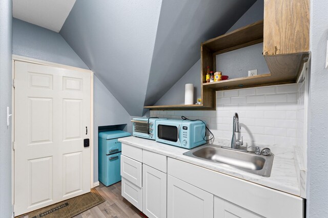 18226 Ennsbury Dr, Houston, TX 77084 - kitchen featuring white microwave, a sink, vaulted ceiling, open shelves, and white cabinetry