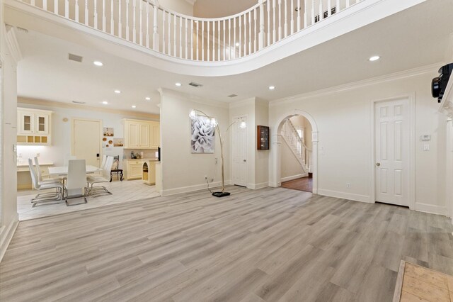 18226 Ennsbury Dr, Houston, TX 77084 - unfurnished living room with arched walkways, crown molding, light wood-style flooring, recessed lighting, and a high ceiling