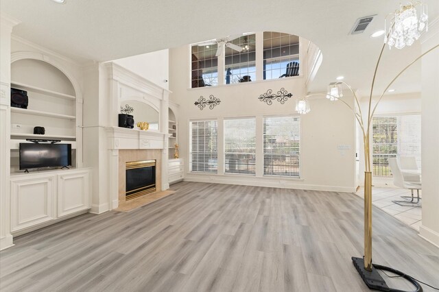 18226 Ennsbury Dr, Houston, TX 77084 - unfurnished living room featuring baseboards, light wood-style floors, a fireplace with flush hearth, built in shelves, and recessed lighting