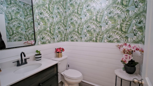 21386 Owl Rd, New Caney, TX 77357 - half bathroom with toilet, vanity, wallpapered walls, and wainscoting
