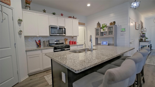 21386 Owl Rd, New Caney, TX 77357 - kitchen with appliances with stainless steel finishes, light wood-style flooring, a kitchen bar, open shelves, and white cabinets