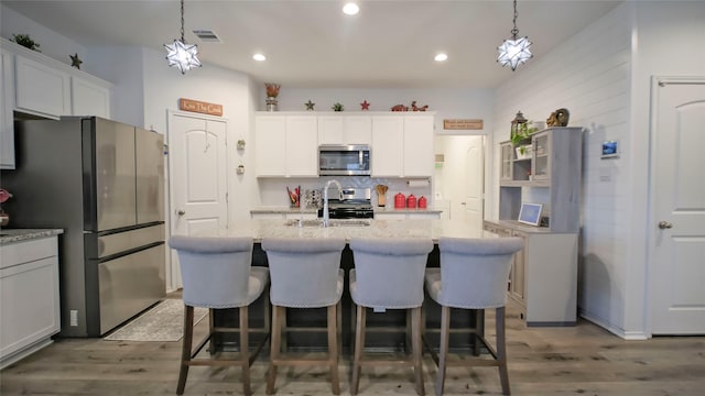 21386 Owl Rd, New Caney, TX 77357 - kitchen with stainless steel appliances, wood finished floors, an island with sink, white cabinetry, and recessed lighting
