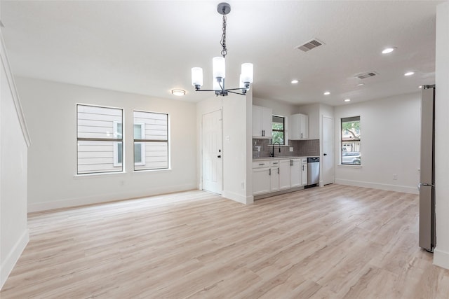 12034 Audubon Hill Ct, Houston, TX 77038 - unfurnished living room with a chandelier, baseboards, light wood-style floors, recessed lighting, and a sink
