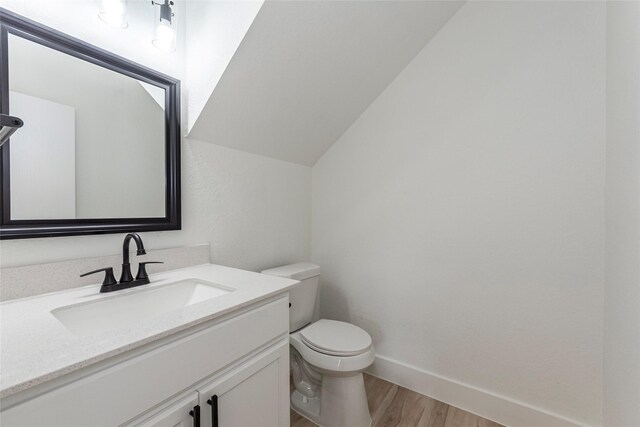 12034 Audubon Hill Ct, Houston, TX 77038 - half bath featuring wood finished floors, toilet, vanity, baseboards, and vaulted ceiling