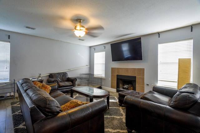 8000 Tee Dr, Austin, TX 78747 - living area featuring dark wood-style flooring, a ceiling fan, a tiled fireplace, and baseboards