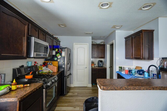 8000 Tee Dr, Austin, TX 78747 - kitchen featuring stainless steel appliances, a sink, dark brown cabinets, light wood-type flooring, and dark countertops