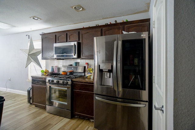 8000 Tee Dr, Austin, TX 78747 - kitchen featuring stainless steel appliances, dark brown cabinetry, backsplash, light wood-style flooring, and baseboards