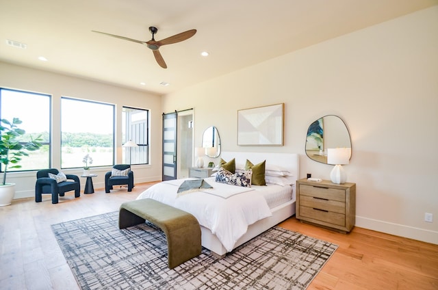 20218 Tealpointe Ridge Ln, Tomball, TX 77377 - bedroom with light wood finished floors, a barn door, recessed lighting, and ceiling fan
