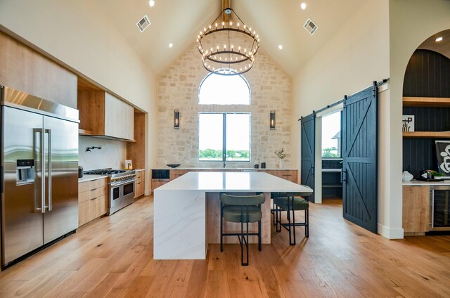 20218 Tealpointe Ridge Ln, Tomball, TX 77377 - kitchen featuring high end appliances, high vaulted ceiling, a barn door, light countertops, and a chandelier