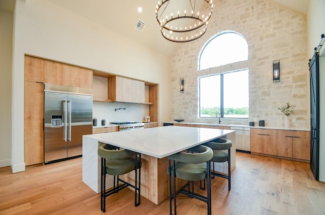 20218 Tealpointe Ridge Ln, Tomball, TX 77377 - kitchen with built in fridge, high vaulted ceiling, a chandelier, light wood-style flooring, and a center island