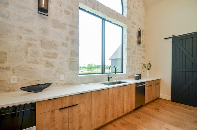 20218 Tealpointe Ridge Ln, Tomball, TX 77377 - kitchen featuring light wood-type flooring, a barn door, modern cabinets, light countertops, and stainless steel dishwasher