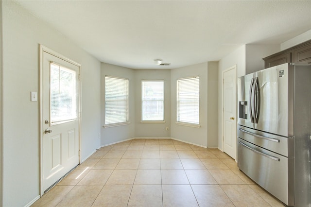 19814 Lindenfield Pl, Katy, TX 77449 - kitchen with stainless steel fridge, plenty of natural light, light tile patterned floors, and baseboards