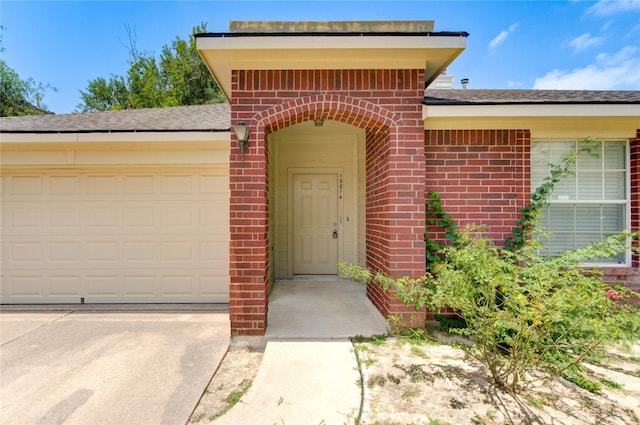 19814 Lindenfield Pl, Katy, TX 77449 - view of exterior entry with brick siding, an attached garage, concrete driveway, and a shingled roof