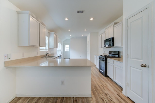 22619 Malvicino Dr, New Caney, TX 77357 - kitchen with black appliances, light countertops, light wood-style floors, a peninsula, and recessed lighting