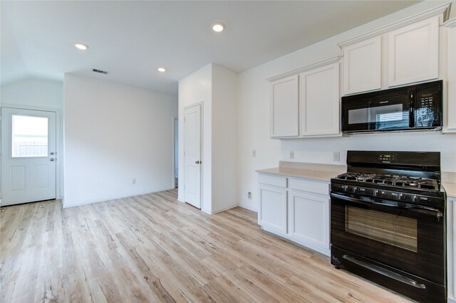 22619 Malvicino Dr, New Caney, TX 77357 - kitchen featuring black appliances, light wood-style floors, light countertops, vaulted ceiling, and white cabinets