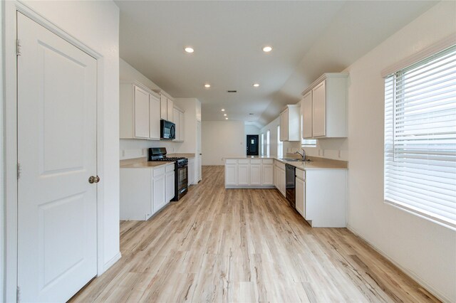 22619 Malvicino Dr, New Caney, TX 77357 - kitchen featuring black appliances, a sink, light wood-type flooring, recessed lighting, and a peninsula