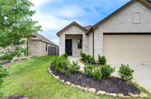 22619 Malvicino Dr, New Caney, TX 77357 - view of front of house with a front yard, brick siding, an attached garage, concrete driveway, and stone siding