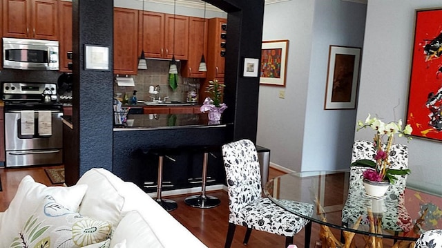 1711 Old Spanish Trl Unit 438, Houston, TX 77054 - kitchen featuring appliances with stainless steel finishes, wood finished floors, backsplash, brown cabinetry, and a sink