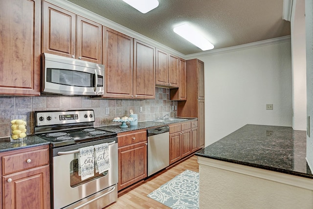 1711 Old Spanish Trl Unit 438, Houston, TX 77054 - kitchen featuring appliances with stainless steel finishes, light wood-style flooring, ornamental molding, decorative backsplash, and dark stone counters